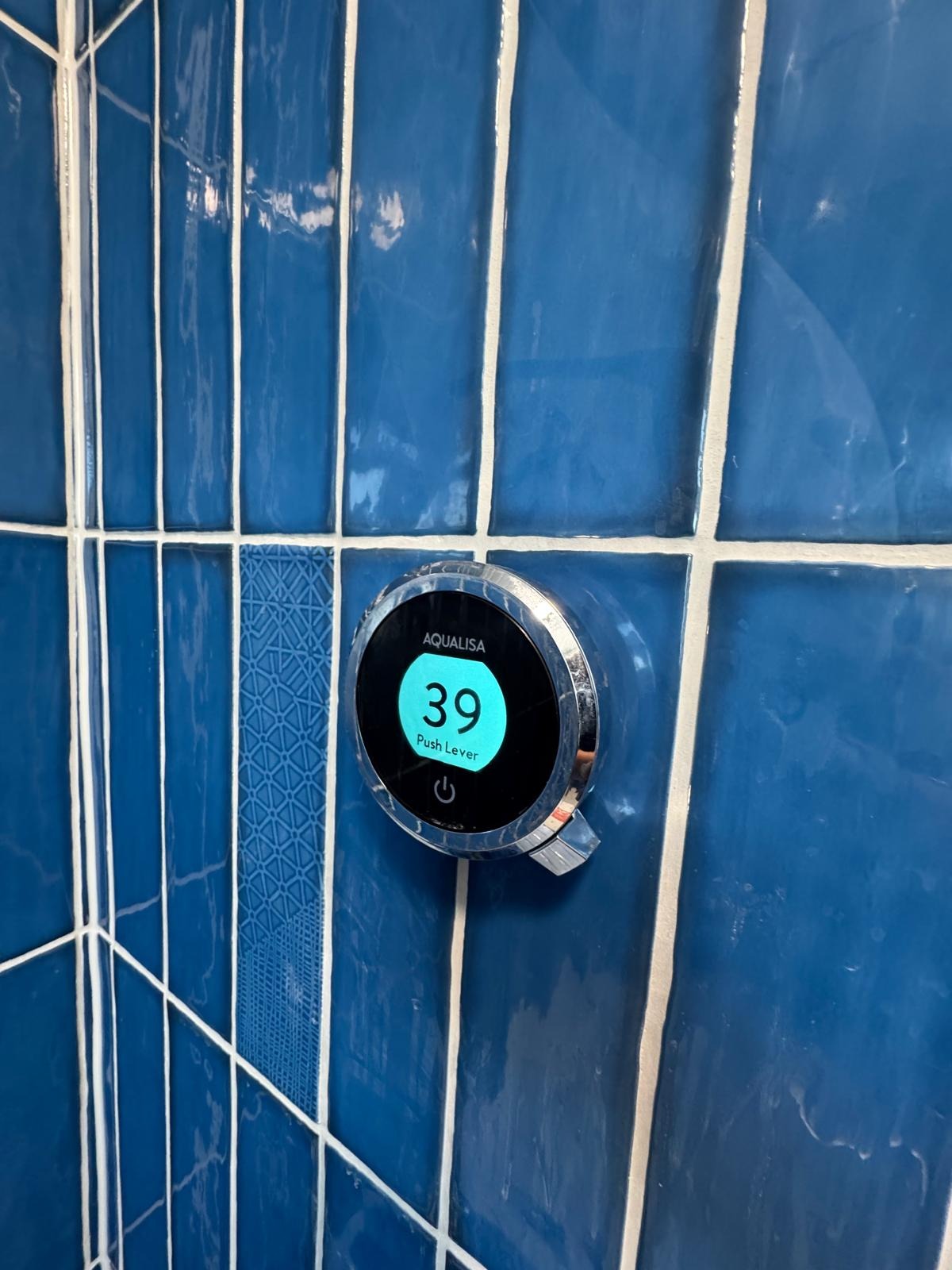 Digital shower control set into blue wall tiling in a completed bathroom refit