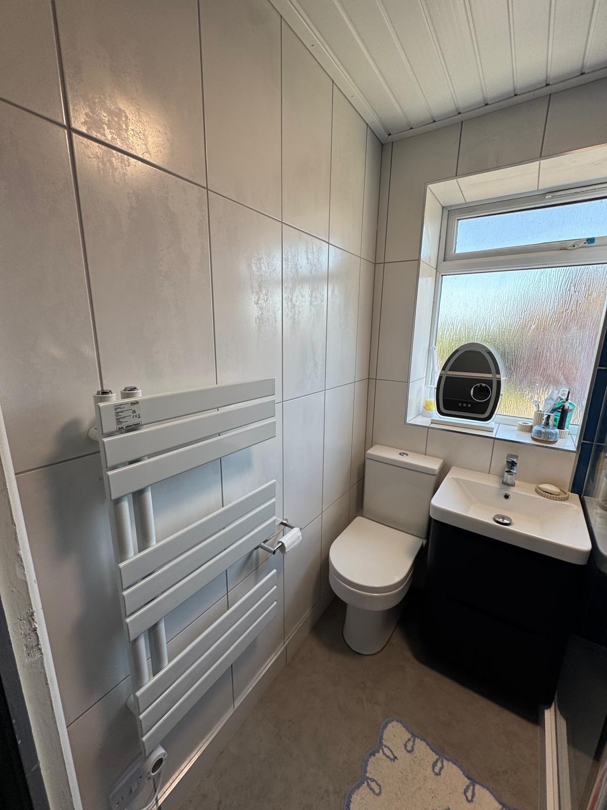 Heated towel radiator and vanity unit in a newly tiled bathroom