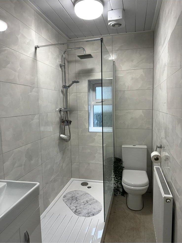 Walk-in shower enclosure with low tray, glass panel and marble-effect tiling