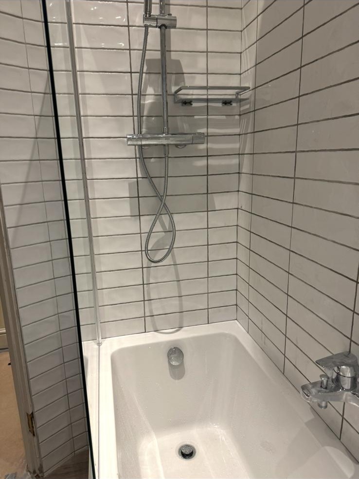 Metro subway wall tiling above a white bath with chrome bath mixer tap