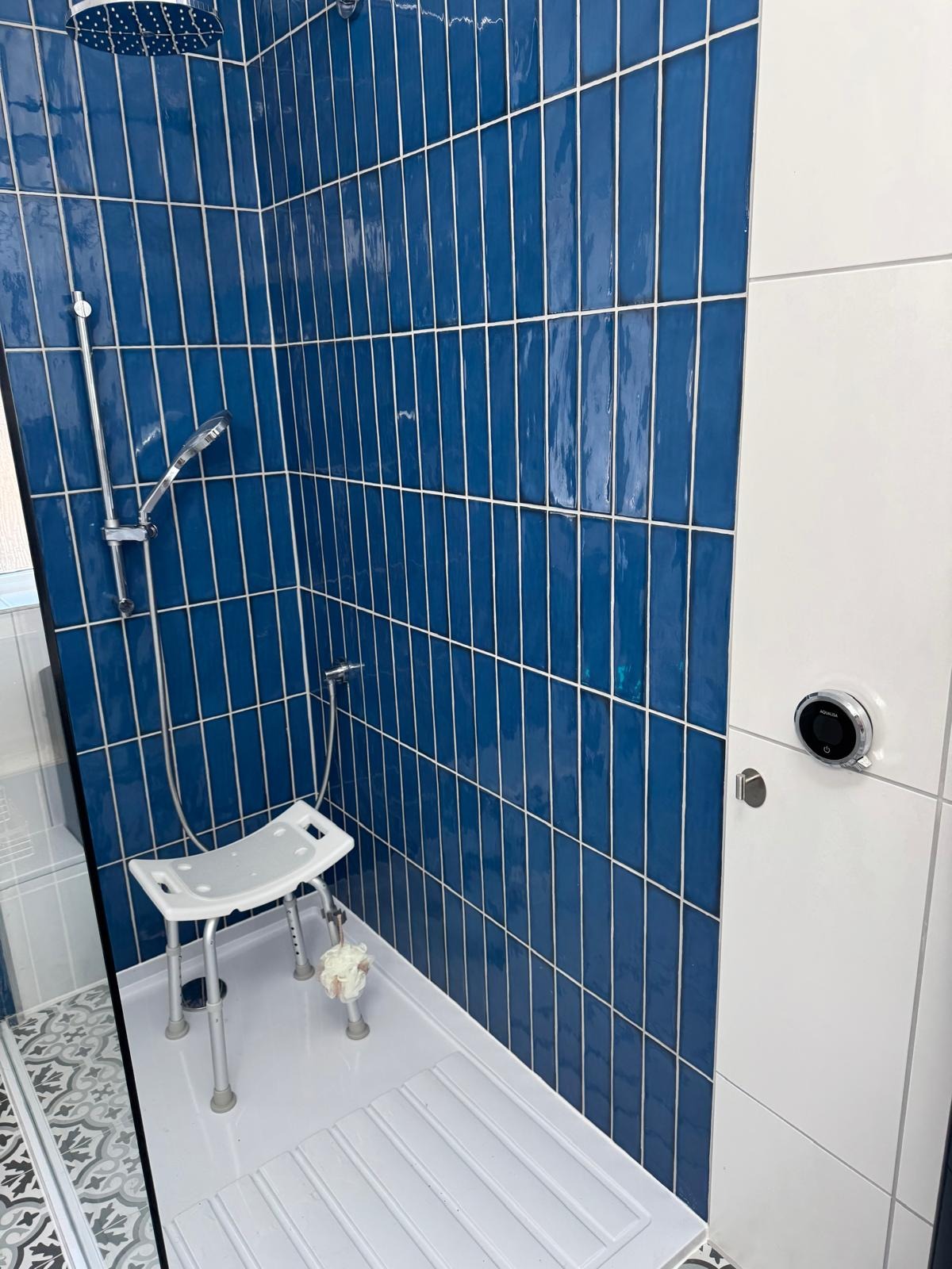 Level-access shower with fold-down seat and digital control in an adapted bathroom