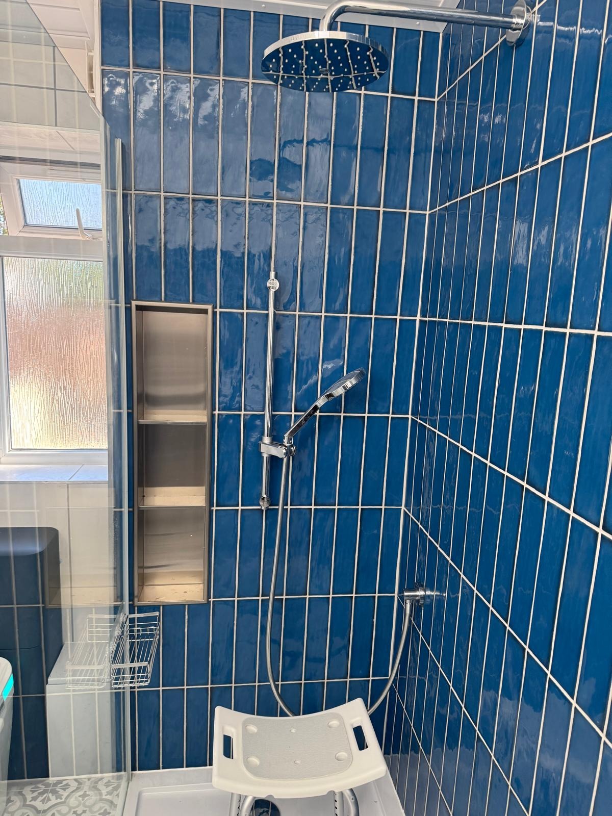 Accessible shower with rainfall head and recessed stainless steel niche