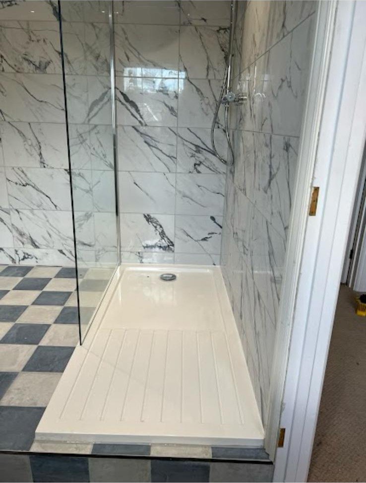 Walk-in shower with marble-effect wall tiles and blue chequerboard floor tiling