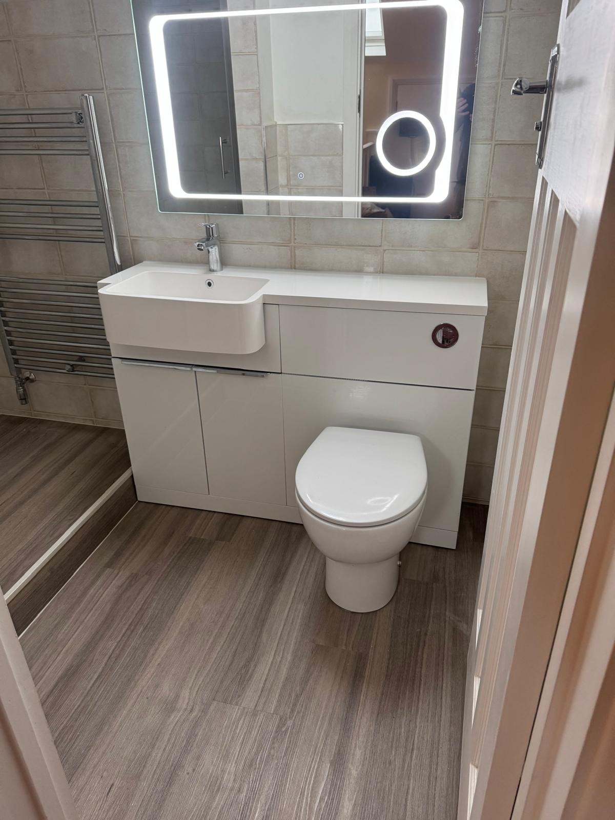Integrated white vanity and toilet unit with large illuminated bathroom mirror