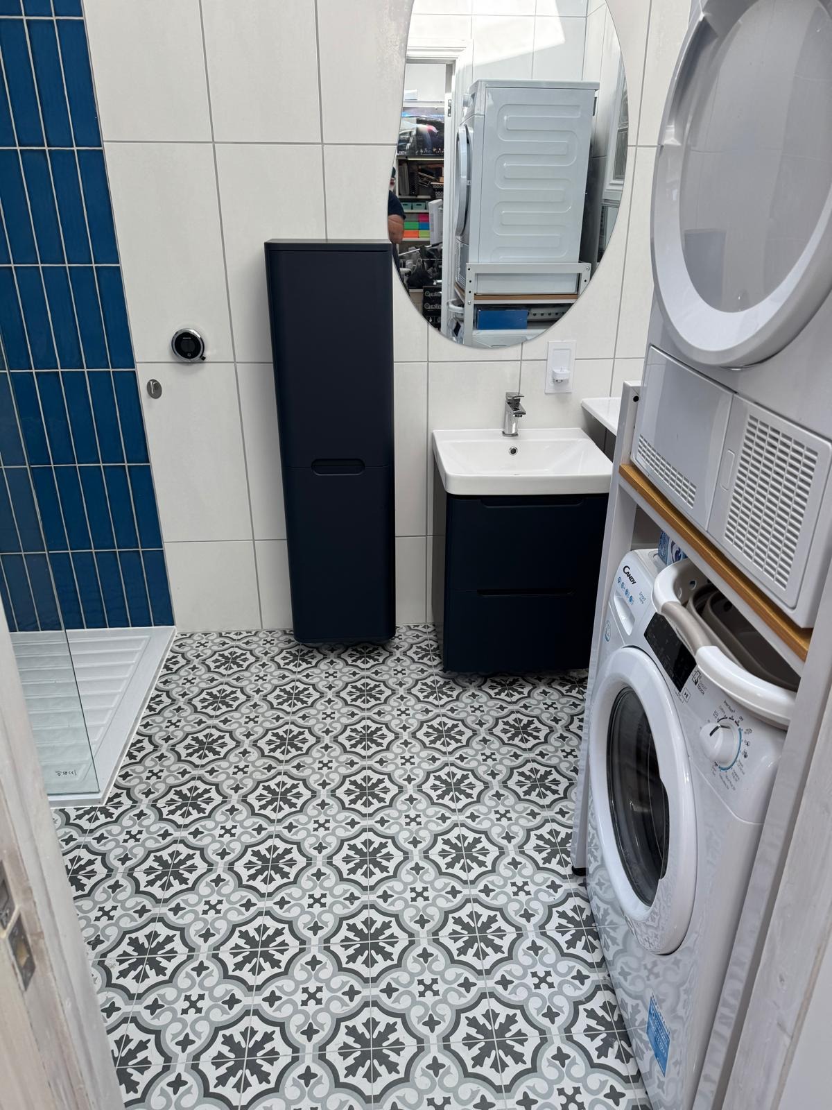 Fitted family bathroom with patterned floor tiles, blue-tiled shower and laundry space
