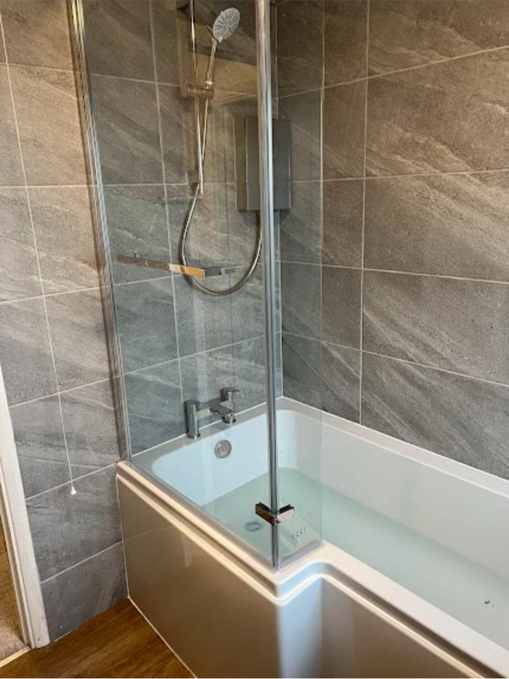 L-shaped shower bath with glass screen and stone-effect wall tiles
