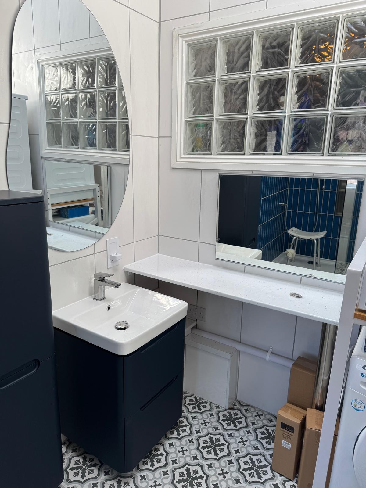 Vanity basin fitted beside a glass block window with a dark blue cabinet