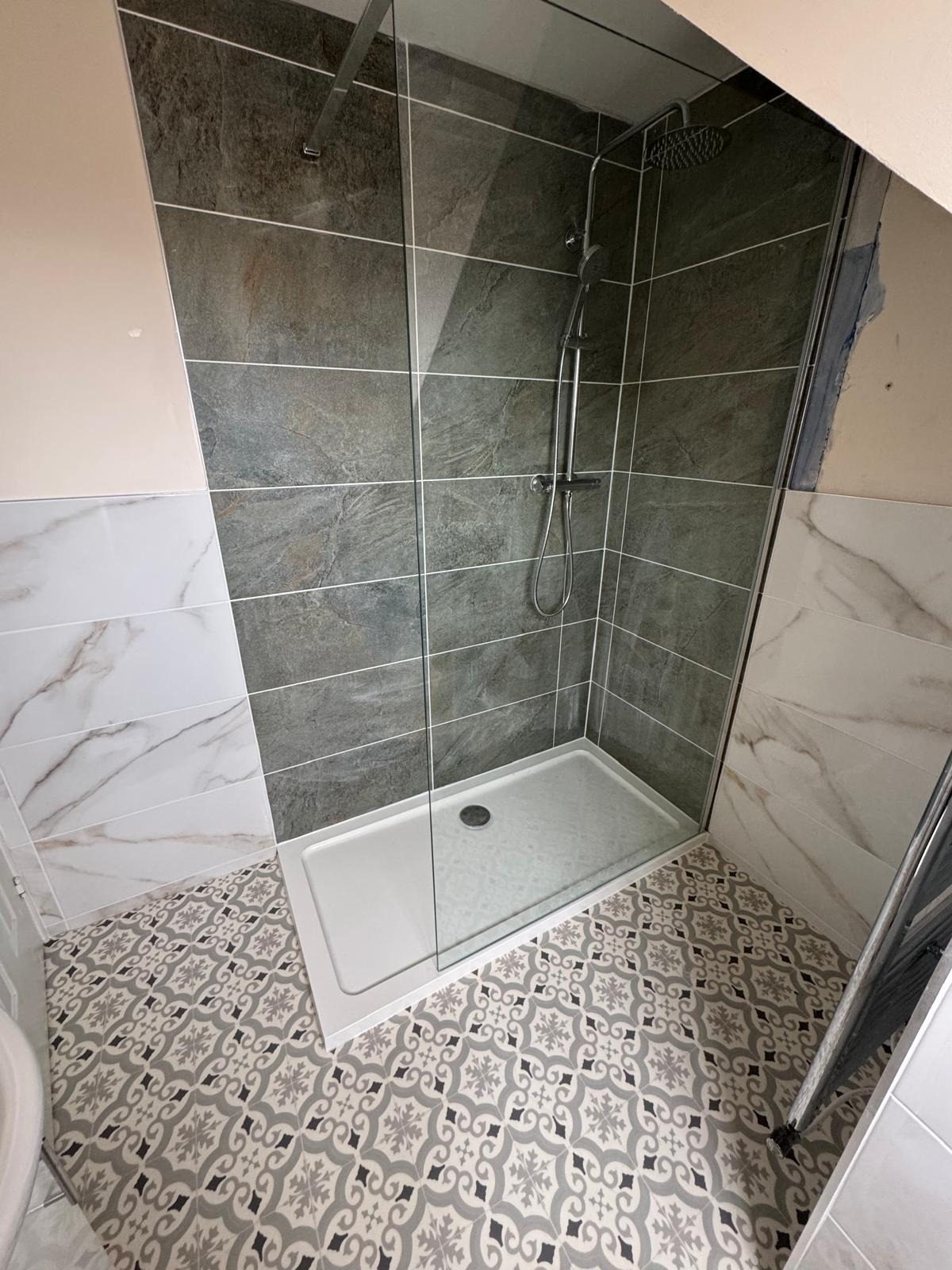 Slate-effect tiled shower area with low-profile tray, glass screen and patterned floor tiling