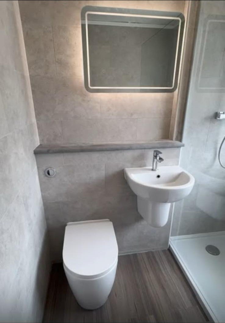 Compact en-suite installation with vanity basin and toilet in beige wall tiles