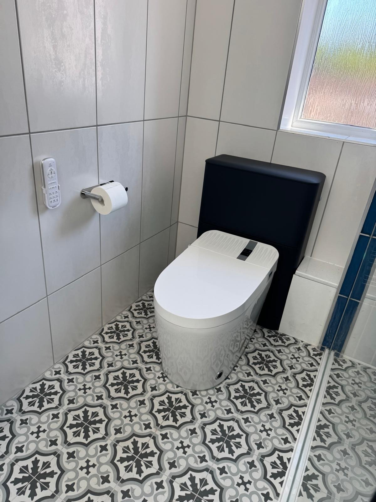 New toilet and patterned porcelain floor tiling in a refitted bathroom