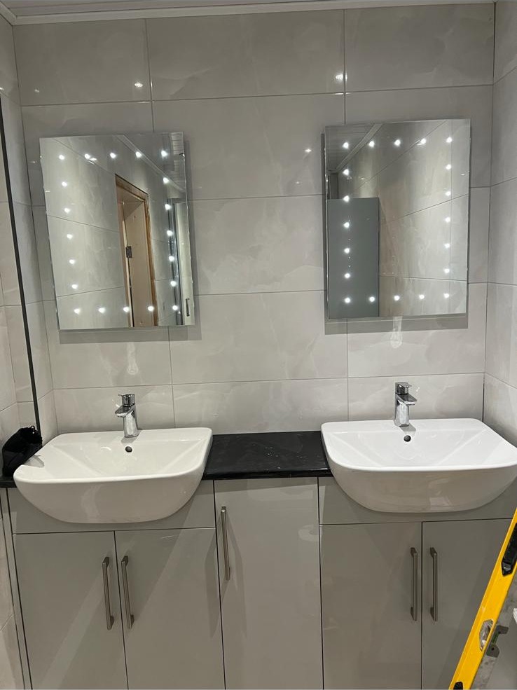 Double vanity basins with illuminated mirrors and grey cabinetry